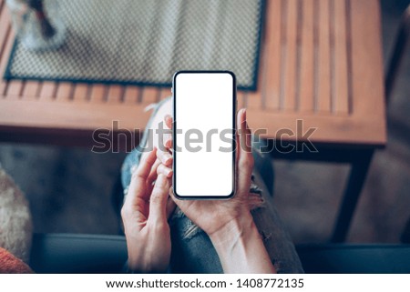 Mockup image woman hand holding texting using black mobile,cell phone at desk with copy space,white blank screen for text.concept for contact business,people communication,technology electronic device