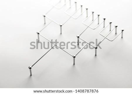 Hierarchy, command chain, company / organization structure or layer concept image. Tournament bracket structure made from chrome wires and nails on white. Shallow depth of field. Royalty-Free Stock Photo #1408787876