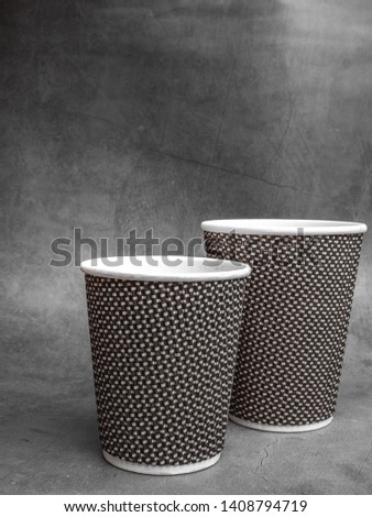 2 sizes of Plastic and Paper coffee cup on grey Table