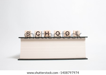 SCHOOL in scrabble letters on hardback book on isolated white background in studio photography