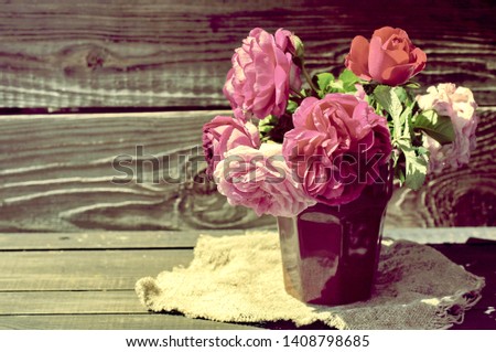 Bouquet of pink peonies in a faceted vase on a wooden table