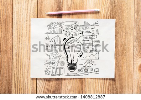 Business infographics pencil hand drawn with group of commercial doodles. Top view of workplace with paper and pencil lying on wooden desk. Financial statistics and analytics. Light bulb and charts