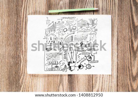 Creative project management pencil hand drawn with group of business doodles. Light bulb idea symbol and financial charts. Top view of workplace with paper and pencil lying on wooden desk.