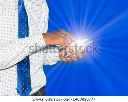 Young indian business man clicking pressing button on mobile phone with light ray on blue colorful background. For customer support of technology artificial intelligence and digital brain marketing