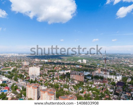 Fluffy cumulus clouds with shadows over the green city
