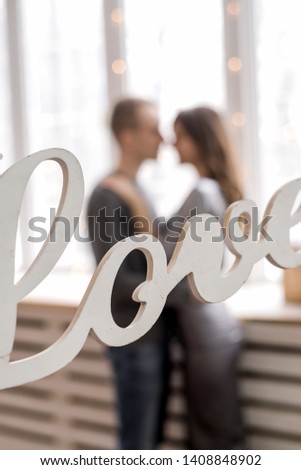 White wooden word love on the background of blurry lovers