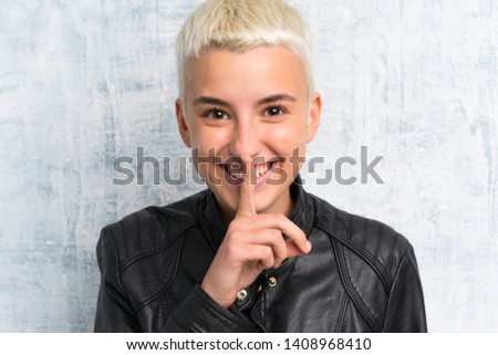 Young woman over grunge wall doing silence gesture