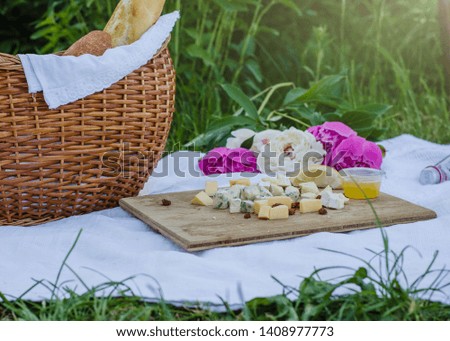 Picnic in the meadow. Cheese, baguette, lemon, fresh water and basket. Close up