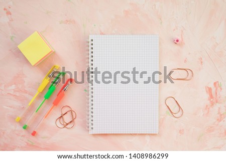 Squared notebook, pens and succulent plant on a student desk workspace, pink backround. Flat lay, top view, mockup, social media hero header template.