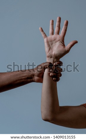 Black African American hand holding white skin arm. Conceptual image of Humanitarian campaign in helping refugees and stop racism issues. World unity cooperation Tolerance and human rights concept.