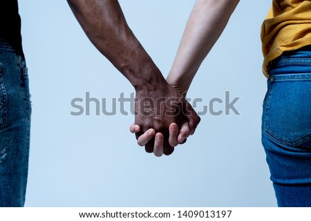 Multiracial couple holding hands together in love. White and black skin arms holding together. Conceptual image of world unity interracial love and understanding in tolerance and diversity. Royalty-Free Stock Photo #1409013197