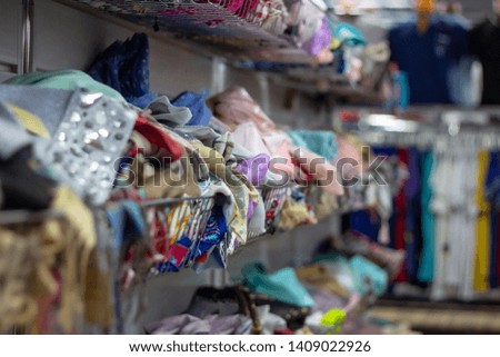 Many different colorful clothes on a hanging rack in the retail shop store. Soft selective focus photography