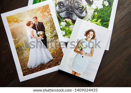 Photo canvas prints. Sample of stretched photography of woman with gallery wrap. Printed photos of a dog and a wedding couple lying on a wooden  table. Top view