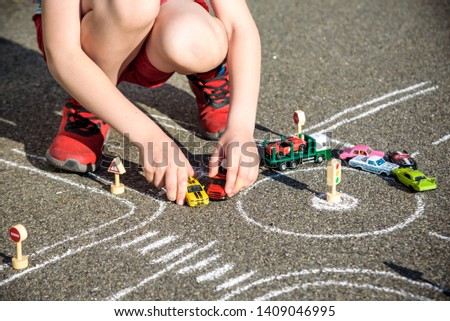 Funny kid boy having fun with picture drawing traffic car with chalks. Creative leisure for children outdoors in summer. Difficult traffic rules concept. Close up