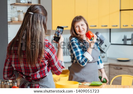 Family cooking blog. Women mother daughter taking photos with smartphone promoting healthy lifestyle diet eating habit