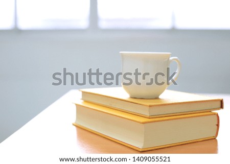 Backlit of yellow books on the table A cup of coffee placed on top selective focus and shallow depth of field