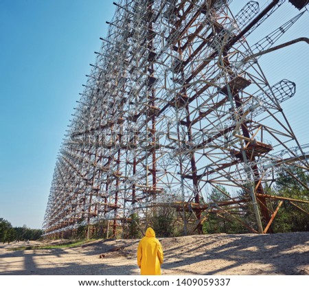 young man in yellow protective suit standing near military secret object antenna radar Duga in Chernobyl in Ukraine, place with higher radioactivity