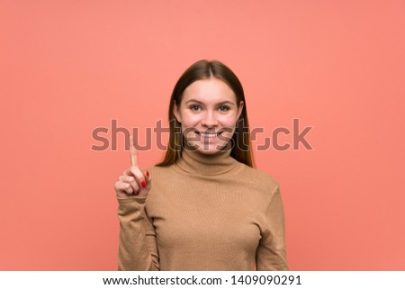Young woman over colorful background pointing with the index finger a great idea