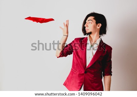 Portrait of young magician making funny gestures isolated on white background