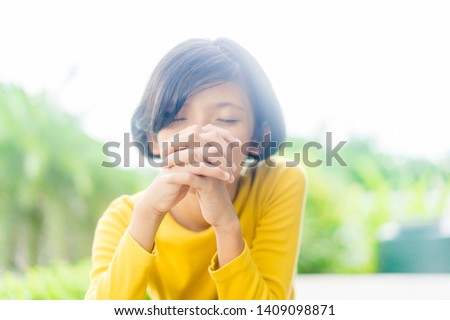 Teenager girl praying in the morning in the park.Little asian girl hand praying,Hands folded in prayer concept for faith,spirituality and religion.