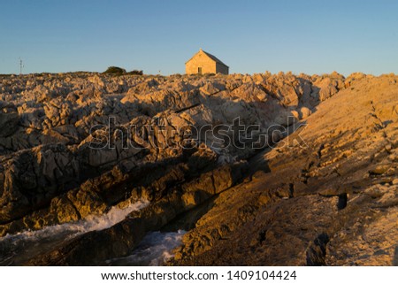 Beautiful nature and landscape photo of coast and small church at Adriatic Sea in Croatia.  Nice outdoors image at sunset. Calm, peaceful spring evening.