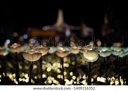 Lotus like flower LED lights set on a field with blur Buddhist temple in background