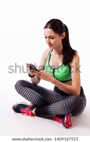 A sport woman  having break during jogging exercise, monitoring her route on mobile phone   on a  white isolated background in studio. Woman runner using running app on gadget to track her progress 