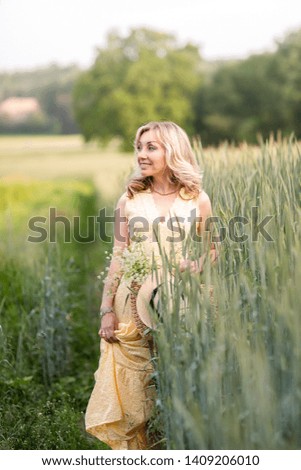 Young beautiful girl with braided bag, straw hat and bouquet color in the field.Summer. Life in the country.