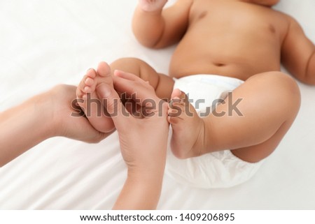 Mother and her cute child on white bed, closeup. Baby massage and exercises