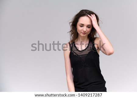 Life is a success. I am pleased with myself. Concept photo of a happy smiling woman satisfied life contented brunette girl in a black T-shirt on a gray background with flowing hair. Made in a studio.