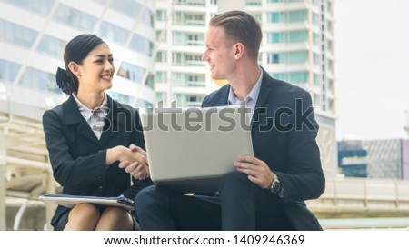 business people lady and caucasian smart man with smart phone and cup of coffee and talk presentation on laptop and shake hand
