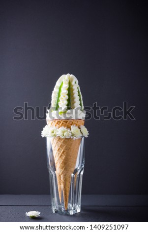 Ice cream cone and white flowers, summer concept. Ice cream with jam on black background. Waffle cone with dessert in glass. Minimalism
