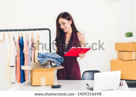 Young woman freelancer working sme business online shopping and packing clothes with cardboard box at home - Business online shipping and delivery concept