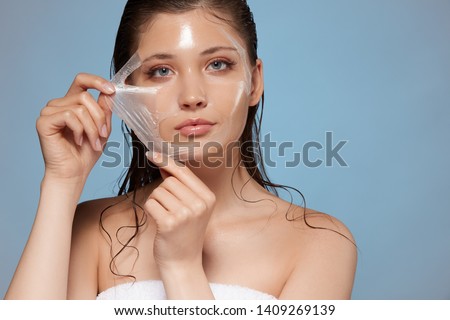attractive woman removing moisturizing mask and looking to the camera, copy space, cosmetology for face, young female face after procedures Royalty-Free Stock Photo #1409269139