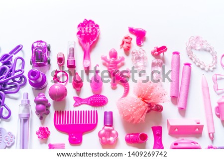 Girly toys for the baby in the pink package. Accessories for dolls. Shoes comb hairpins and varnish. White background