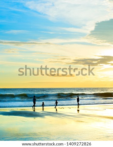 Family walking at sandy beach, sunset seascape, Bali, Indonesia