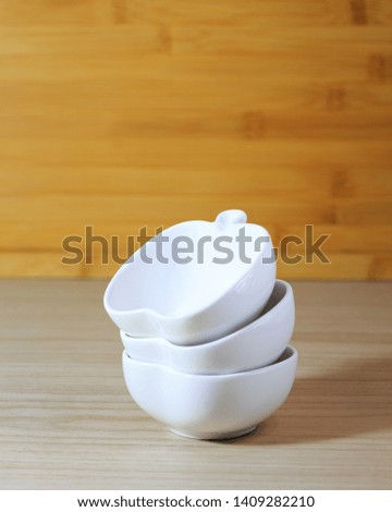 Closeup kitchenware, 3 white ceramic bowls of apple shape design on wood dining table background-soft focus