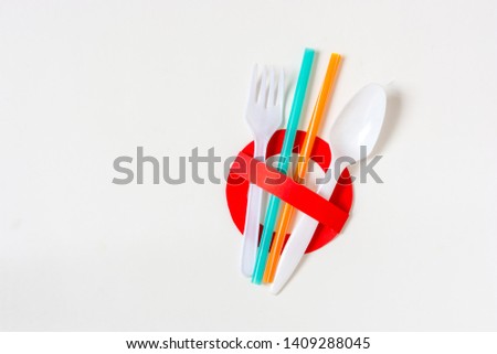 Ban single use plastic. A creative artwork of stop sign over colorful plastic straws, fork, spoon, on white background. Pollution/environmental concept. Say no to plastic. Save the world.