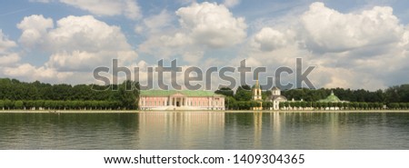 Russian noble estate on a sunny summer day. The building of the eighteenth century, the church, the pavilion on the shore of a large pond. Well-groomed park with trimmed trees. Royalty-Free Stock Photo #1409304365