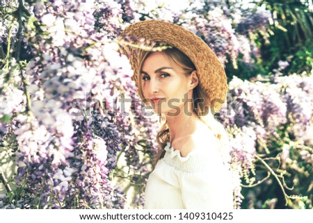 Portrait of a beautiful caucasian blonde woman, european retro style, romantic image, spring blooming of wisteria, magnificent clusters of flowers.