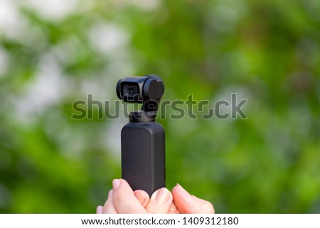 Close up picture of black osmo device, pocket camera - ideal tool for travel photography and videography - green background