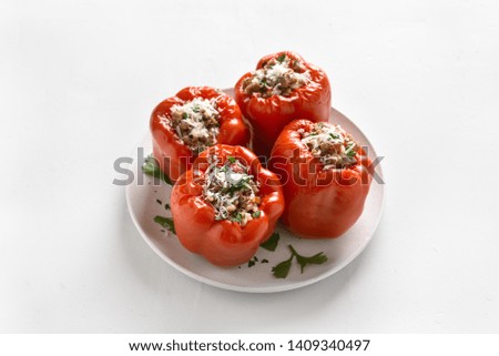 Close up of baked red bell pepper filled with minced meat, rice, parmesan cheese on white stone background.