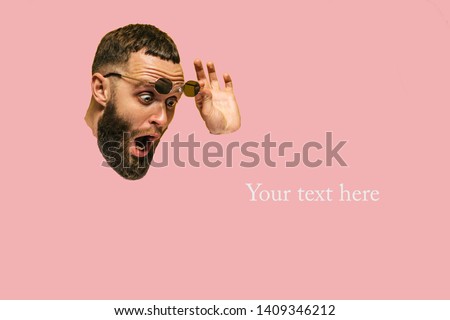 Suprised weird bearded hipster man making hole in paper. Blank space for advertising, to insert your text. Royalty-Free Stock Photo #1409346212