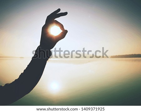 Fingers gesturing picture frame on sunrise seaside. Sunlight on beach. Sunset at the sea. Hand-made gesture in love concept.