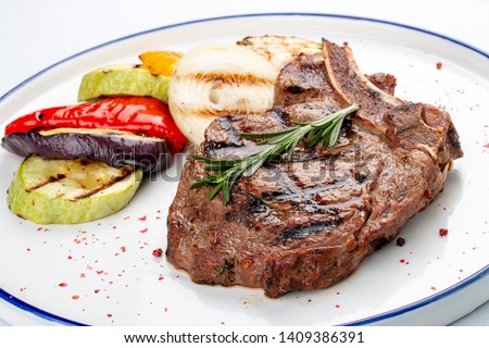 Veal bone steak with grilled vegetables on a white background