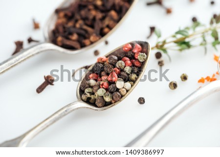close up view of pepper mix in silver spoon on white background