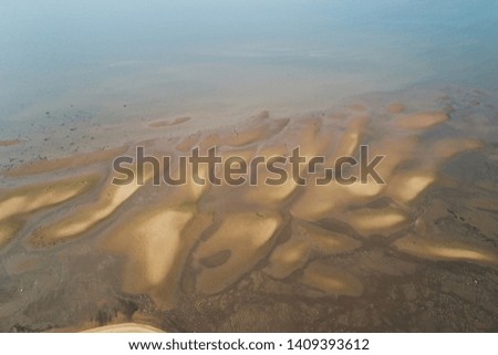 Top view of the sandy beach sea with a beautiful pattern formed from the water, in the bright sunset light in summer. Photography with drone in the form of texture and background