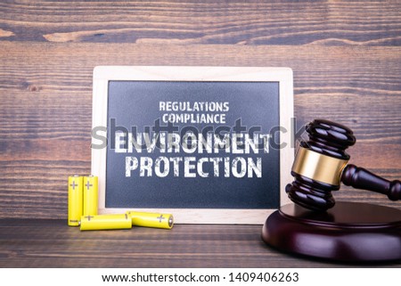 Environment Protection, Regulations and Compliance concept. Chalk board, court hamme and AA size batteries on wooden background