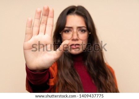 Teenager girl with coat making stop gesture with her hand