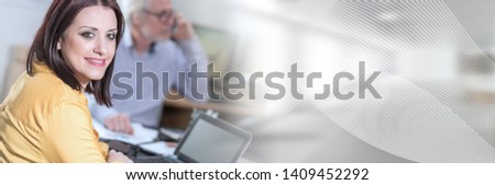 Portrait of young businesswoman sitting at desk in office, light effect; panoramic banner
